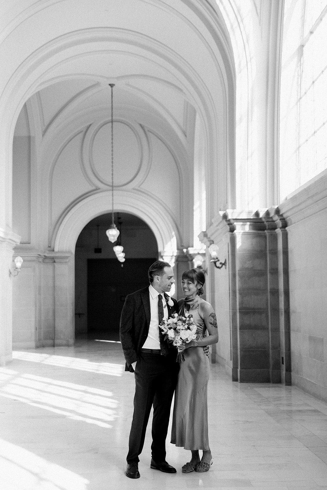 black and white photo of bride and groom in hallway at san francisco city hall