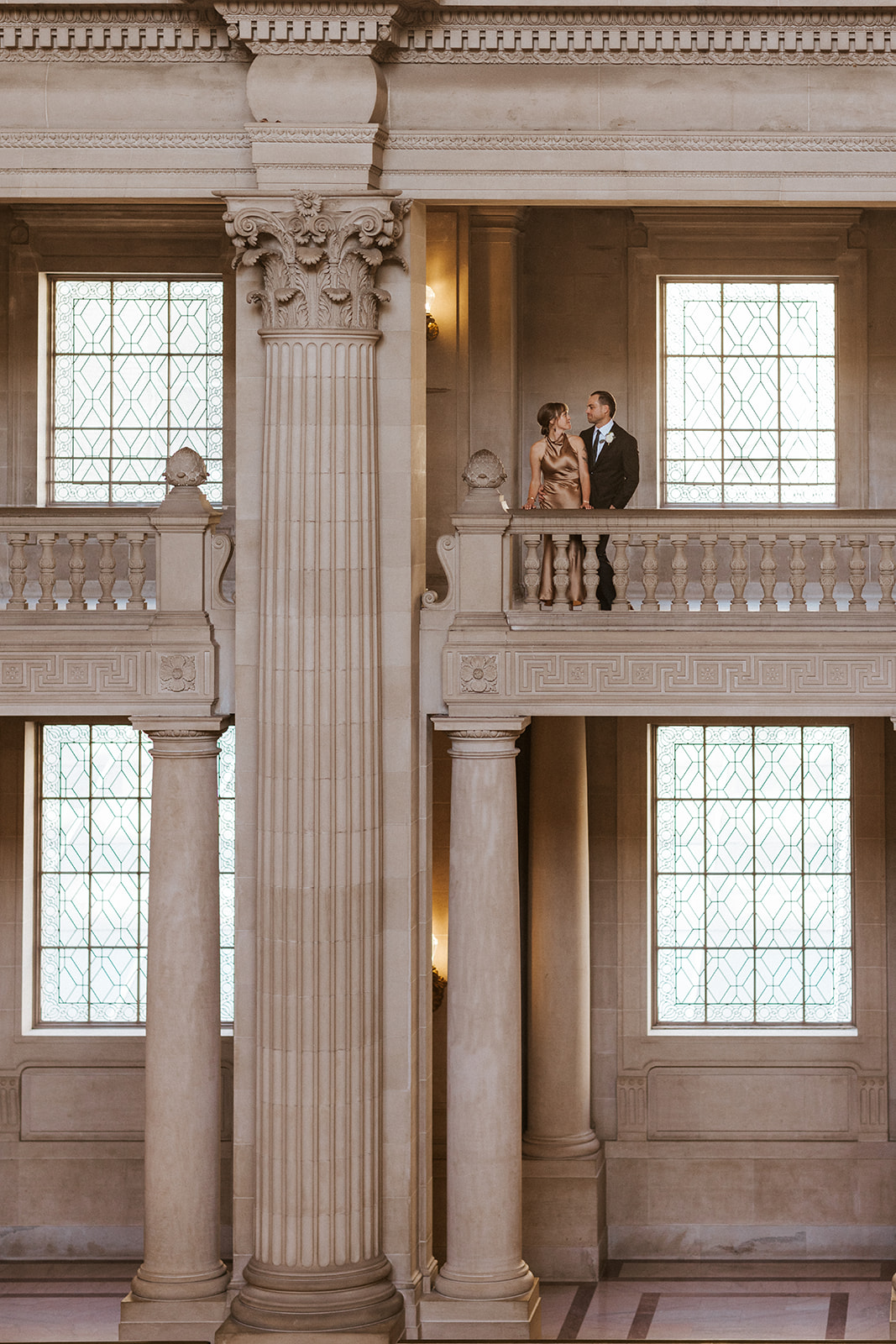 bride and groom posed on balcony at san francisco city hall