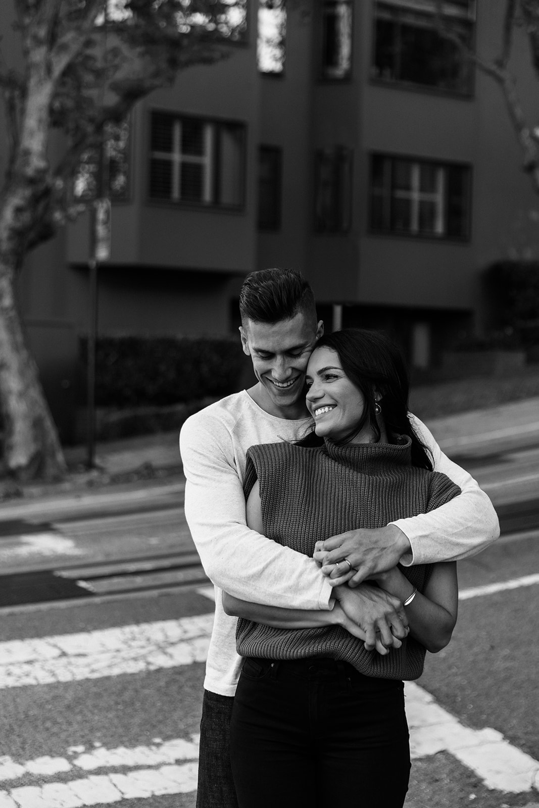 black and white image of couple cuddling by road in san francisco russian hill