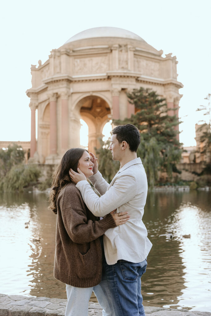 couple posing in front of lake at palace of fine arts in san francisco